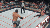 a referee stands in the middle of a wrestling ring with a man laying on the floor