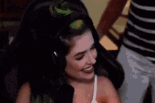 a man and a woman are hugging each other and smiling . the woman has green hair .