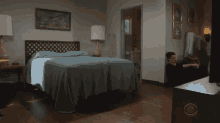 a bedroom with a bed and a cbs logo