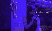 a woman is singing into a microphone in a purple room