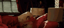 a person is laying in bed with a red blanket and a white pillow with a tattoo on it .