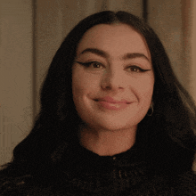 a woman wearing a black sweater and hoop earrings smiles for the camera