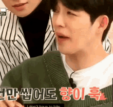 a man in a green sweater is crying while another man looks on .