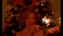 a woman is holding sparklers in her hands in front of a christmas tree .