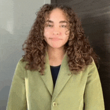 a young woman with curly hair wearing a green jacket