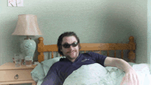 a man wearing sunglasses is laying in bed with a lamp