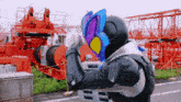 a man in a superhero costume holds a sword in front of a construction site
