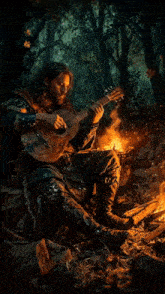 a man playing a guitar in front of a fire in the woods