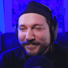 a man with a beard is wearing headphones and smiling .