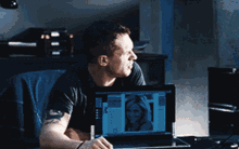 a man sitting at a desk looking at a laptop screen