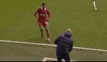 a soccer player is being helped off the field by a man in a jacket
