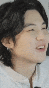 a close up of a person 's face with a white shirt on and earrings .