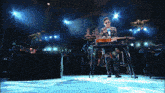 a man playing a guitar on a stage with a sign in the background that says river island