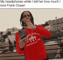a man in a red shirt is holding a cell phone and wearing headphones while talking to someone