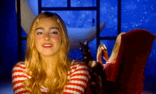 a woman in a red and white striped shirt is sitting in a chair