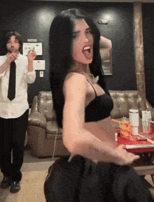 a woman in a bra is dancing in front of a man in a tie