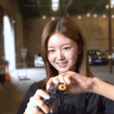 a woman is smiling while holding a small object with a circle in the middle