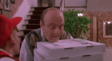 a man is holding a stack of pizza boxes in front of him .