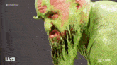 a bearded man is covered in green slime .