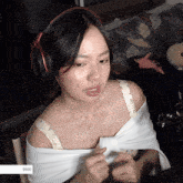 a woman wearing headphones and a white shirt is sitting in front of a $ 500 sign