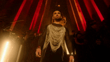 a man in a black and silver outfit stands in front of a crowd of people