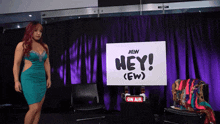 a woman in a green dress is standing in front of a sign that says hey