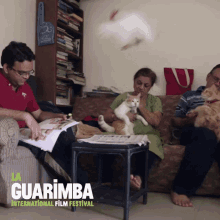 a poster for the guarimba international film festival shows a family sitting on a couch with cats