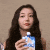 a woman is holding a bag of juice in her hand and drinking from it .
