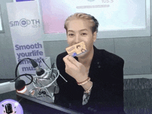 a man holding a card in front of a sign that says smooth 105.5