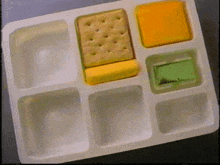 a plastic tray filled with crackers cheese and a green sandwich
