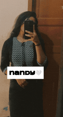 a woman is taking a picture of herself in a mirror with the name nandy on the bottom right