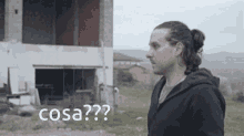 a man in a black jacket is standing in front of a building with the word cosa written on the bottom