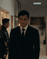 a man in a suit and tie stands in a hallway next to a man in a black jacket with the word polis on it