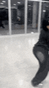 a woman is dancing in a room with a lot of windows and a mirror .