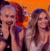 a man and a woman are sitting next to each other on a stage and the woman is clapping .