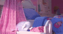 a crib with a pink canopy and a blue bed