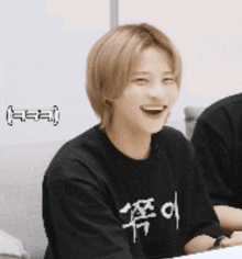 a man wearing a black shirt with chinese writing on it is smiling .