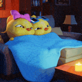 a couple of stuffed chickens laying on a couch with a blue blanket