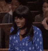 a woman wearing a blue polka dot shirt is smiling