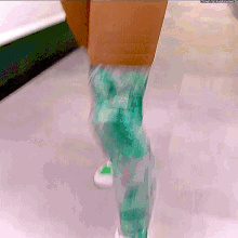 a person wearing green pants and white shoes is walking in front of a cardboard box