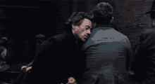 a group of men are standing next to each other in a dark room and shaking hands .