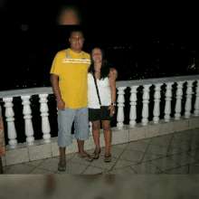 a man in a yellow shirt is posing for a picture with a woman
