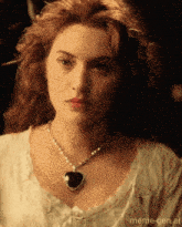a woman with red hair wearing a heart shaped pendant