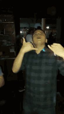 a young man in a plaid shirt is dancing in a dark room