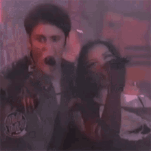 a man and woman are singing into microphones in a dark room .