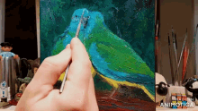 a person is painting a blue and green bird on a canvas with made in animatica written on the bottom