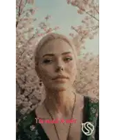 a woman in a green dress is standing in front of a tree with cherry blossoms .