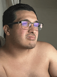 a man without a shirt is wearing glasses with a reflection of his eyes