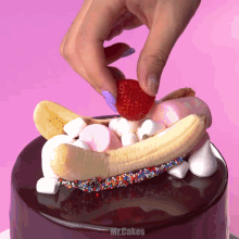 a person is putting a strawberry on top of a chocolate cake with marshmallows