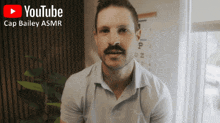 a man with a mustache looks at the camera with a youtube logo behind him